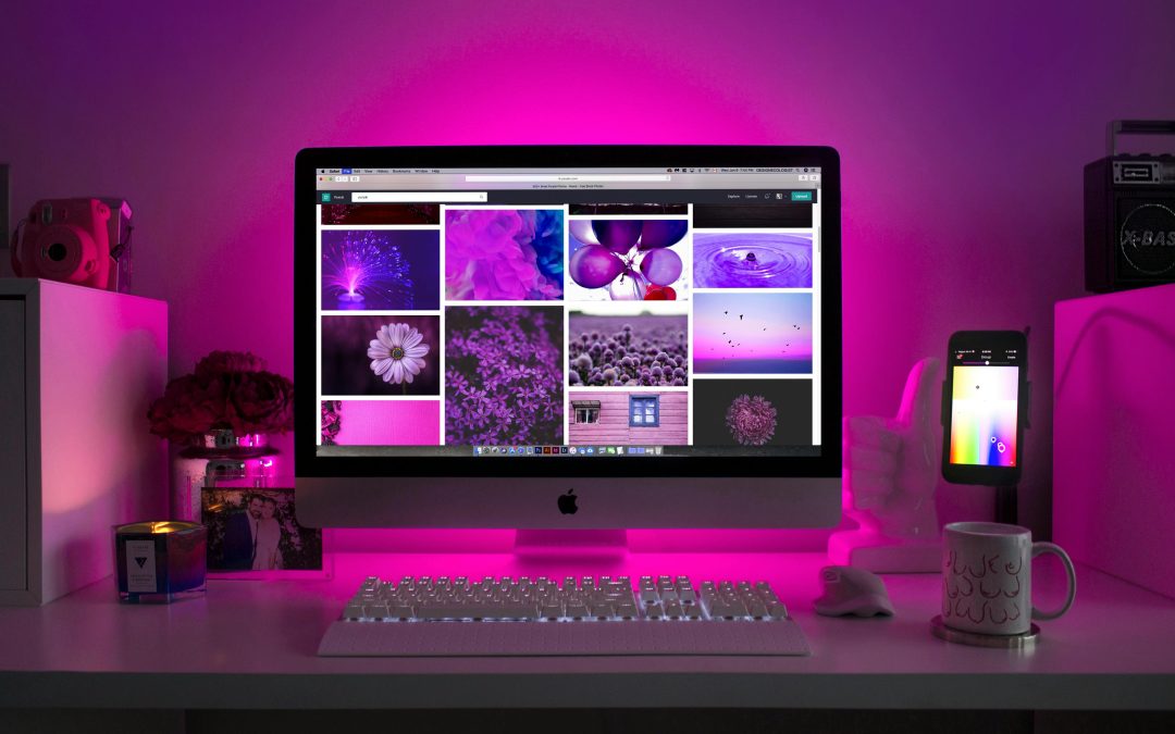 Modern desk setup with neon lighting and a desktop computer displaying colorful images.